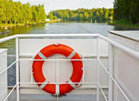 Life ring on a boat's deck with river and forest in background