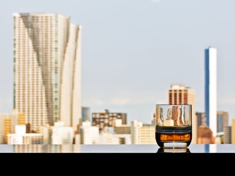 A glass of whisky with panoramic view of Tokyo on a background