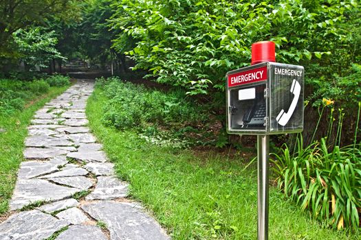 Emergency telephone booth in the park near a paved track