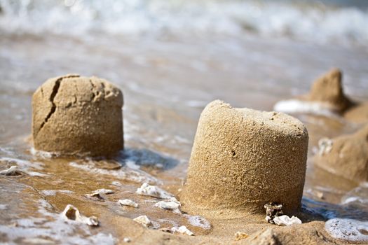 Sand pies at a sea coast dissolving by surf