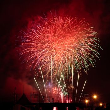 Red fireworks in the black sky over the railway bridge