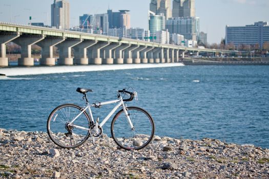 White road bicycle at the riverside with river and city on background