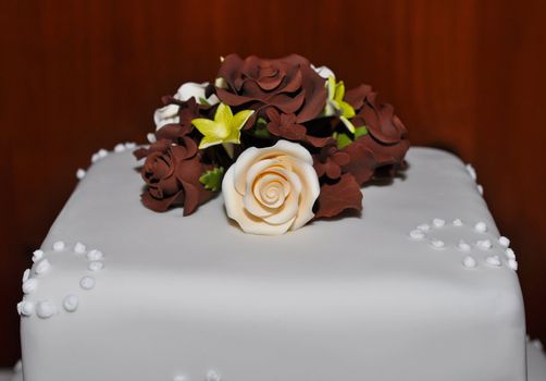 White fondant wedding cake with pink and brown roses