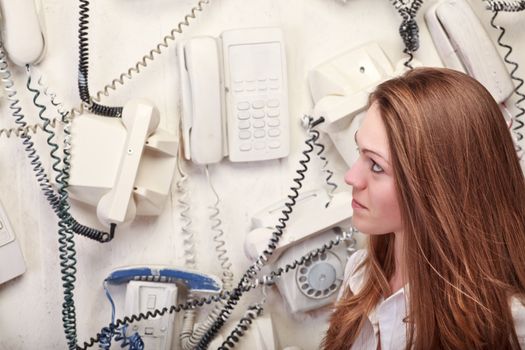 woman with vintage phones on wall
