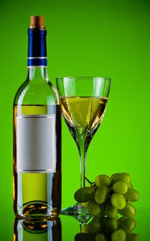 bottle and glass of wine, grape bunch, green background