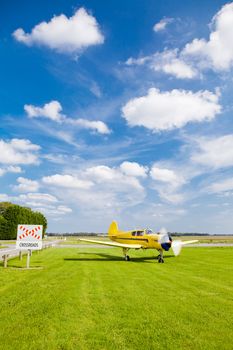 An old propeller plane yellow near a crossroads