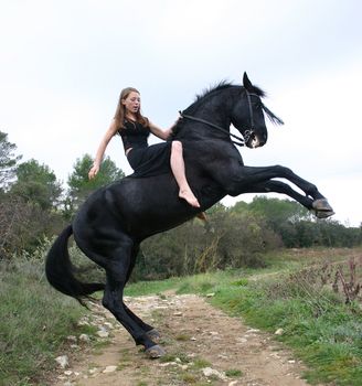 rearing black stallion and young woman in a field