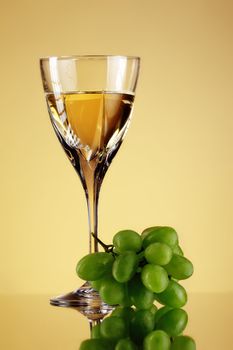 glass of wine and grape bunch, beige background