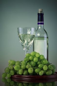 bottle and glass of wine, grape bunch, gray background