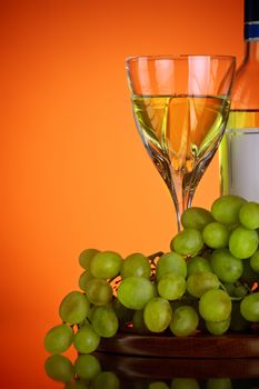 glass of wine and grape bunch, red background
