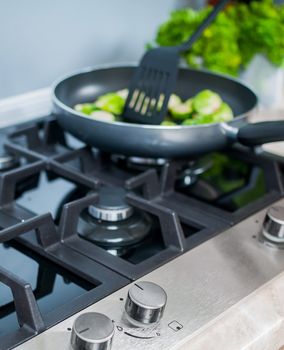 gas-stove with vegetables dish prepared in a black skillet in the kitchen