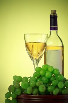 bottle and glass of wine, grape bunch, green background