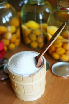 An image of pot of sugar and jars with apricots