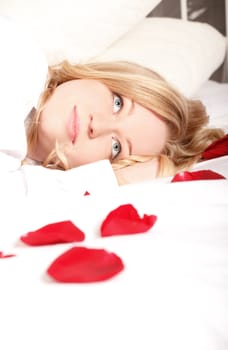 blonde woman in bed with red rose petals
