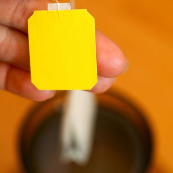 Part of womans hand holding tea bag