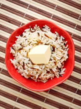 red bowl with cooked rice and butter on bamboo napkin