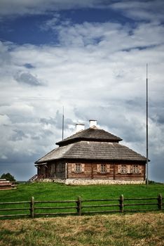 wooden cottage on green hill under cloudy sky