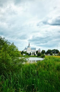 monastery on calm lake at cloudy day