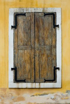 An image of wooden window closed on yellow wall