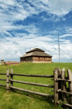 wooden cottage on green hill under cloudy sky