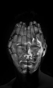 Surreal portrait of a young man covering his face with his hands, but he can see through them.