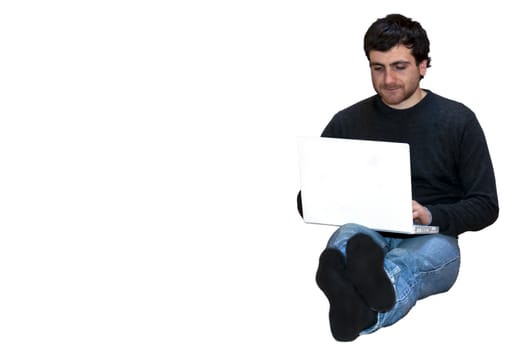 young man sitting on the floor cross-legged with laptop.