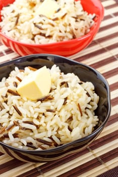 bowls with cooked rice and butter on bamboo napkin