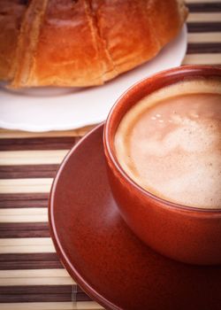 fresh coffee cup and croissant on bamboo napkin