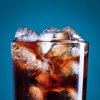 glass of cola with ice on blue background