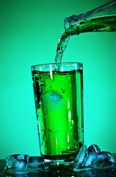 pouring soda in glass over green background