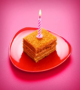 birthday cake with candle on pink background