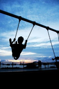 Man playing swing under sunset