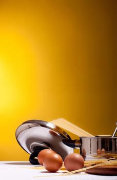 spaghetti, eggs, cheese and utensils on table