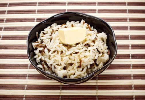 black bowl with cooked rice and butter on bamboo napkin