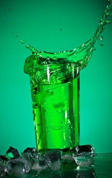 glass with splashing soda on green background