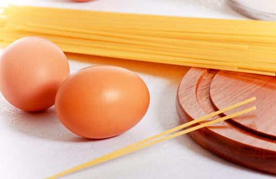 spaghetti, eggs and kitchen utensil on white background