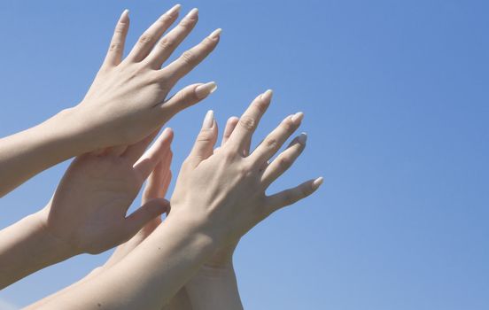 Female hands are lifted to a blue unflawed sky