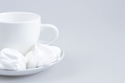 White ceramic cup and cakes on a light gray background