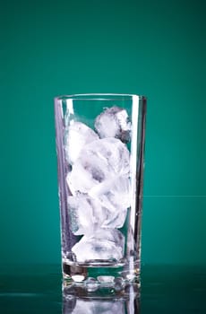 glass full of ice on green background