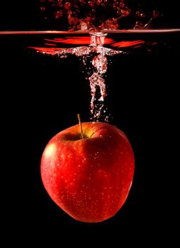 apple falling to water with splash over black background