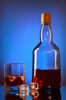 whiskey bottle and glass on blue background