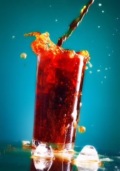 pouring cola in glass over blue background