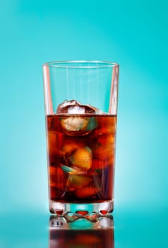 glass of cola with ice on blue background