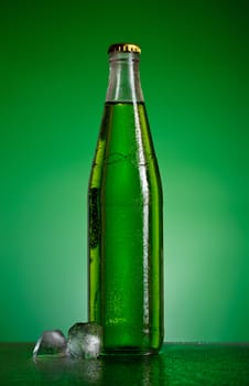 green soda bottle and ice cubes, green background