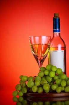 bottle and glass of wine, grape bunch, red background