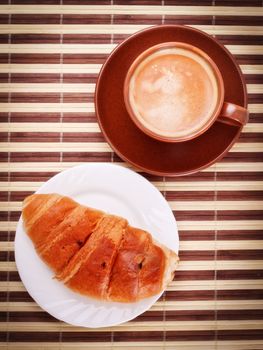 fresh coffee cup and croissant on bamboo napkin