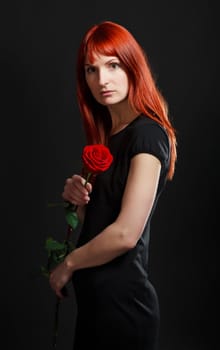 girl in black dress with red rose, black background
