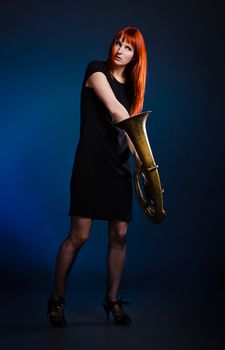 girl in black dress with trumpet, blue background