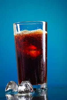 glass of cola with ice on blue background