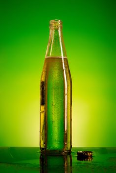 green soda bottle and ice cubes, green and yellow background